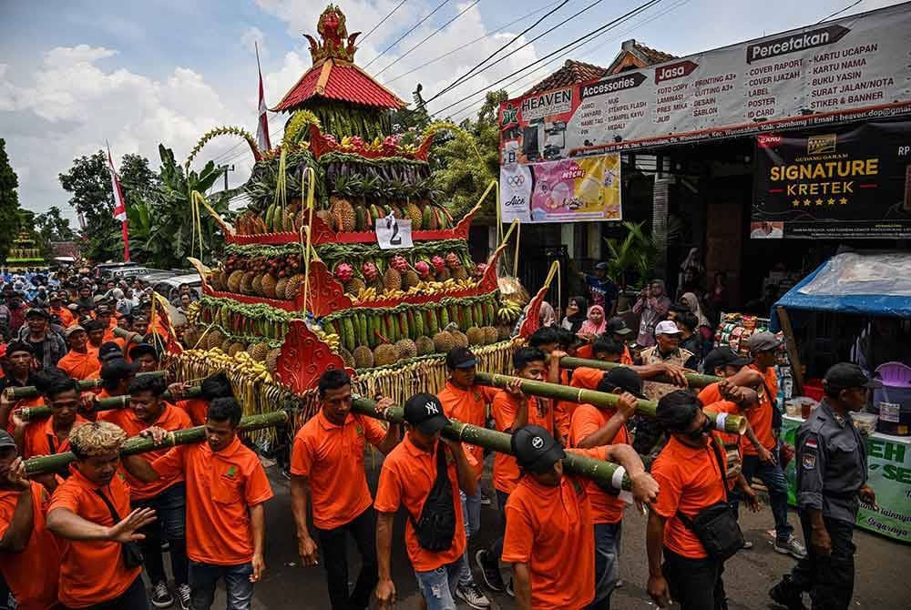 Peserta berarak dengan membawa perahu hiasan yang dihiasi durian dan buah-buahan lain semasa festival berkenaan pada Ahad.