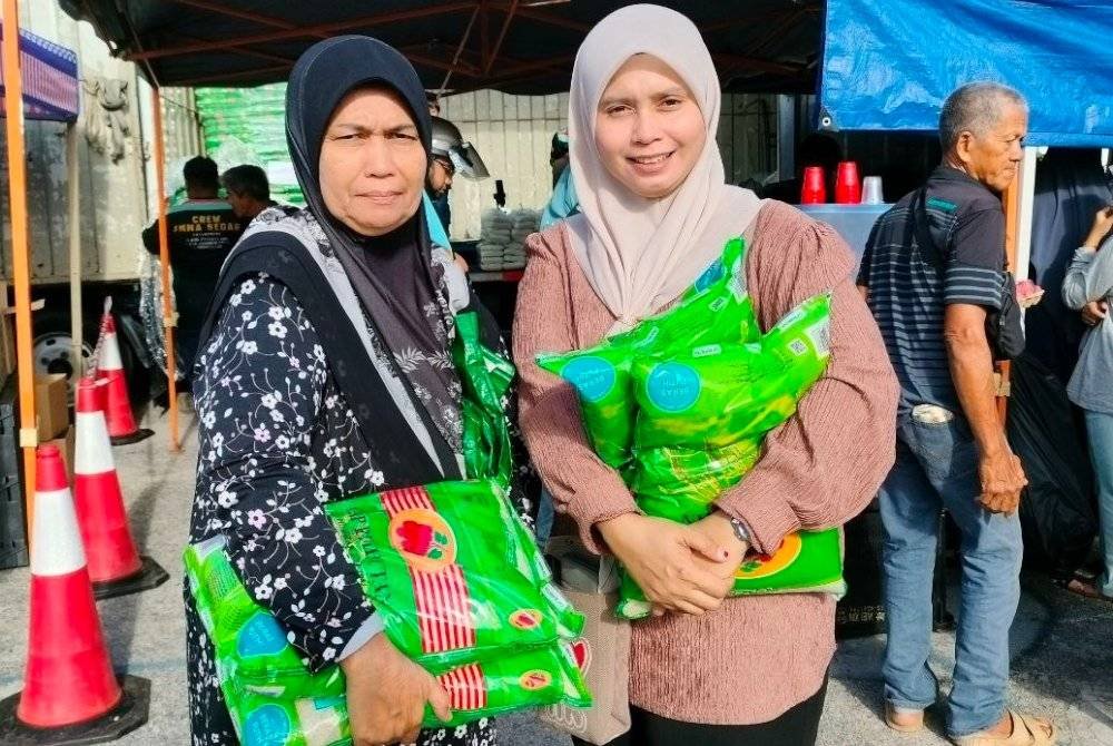 Siti Mariam (kanan) dan ibunya, Che Zaiton lega dapat membeli beras putih tempatan.