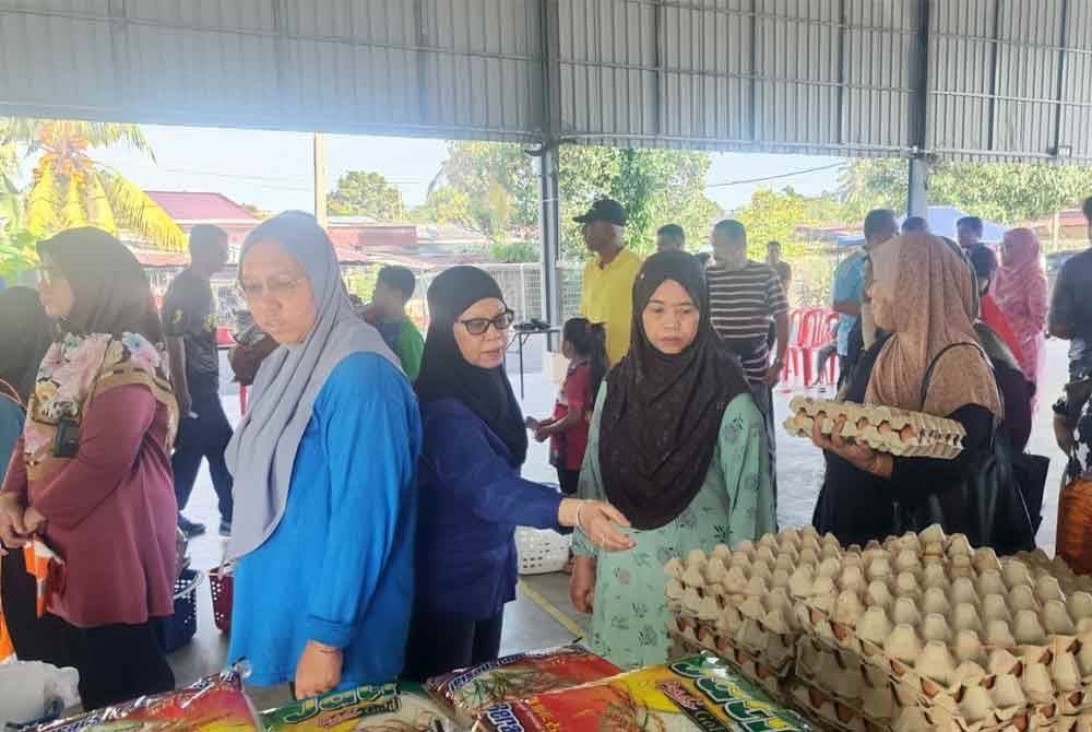 Tengku Zamrah (tiga dari kiri) menyantuni orang ramai pada Program Jualan Rahmah Madani DUN Ampangan yang diadakan di Dewan Orang Ramai Taman Dusun Nyior dan Pasar Ampangan pada Sabtu.