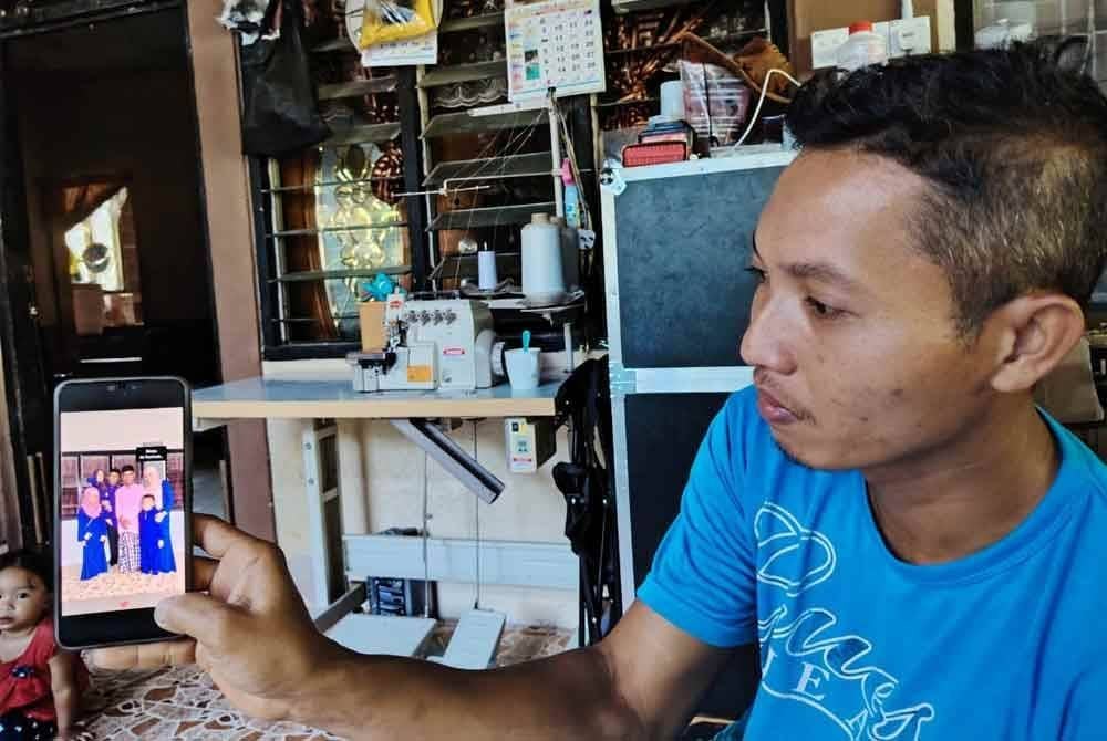 Mohd Azam menunjukkan gambar arwah ayah ketika sambutan Aidilfitri tahun lalu.