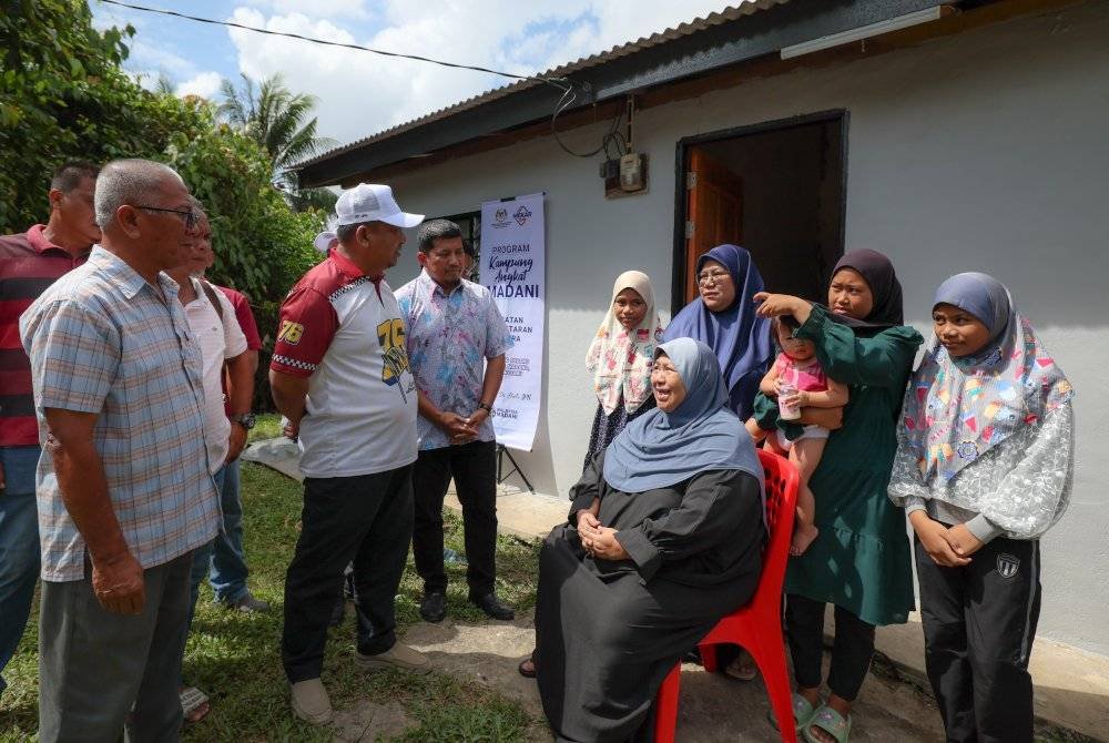 Badrul Hisham (dua, kiri) menyantuni warga emas, Kelsom Mohamed, 66, (duduk) menerusi Program Kampung Angkat Madani di Kampung Padang Tanjung pada Sabtu. Foto Bernama