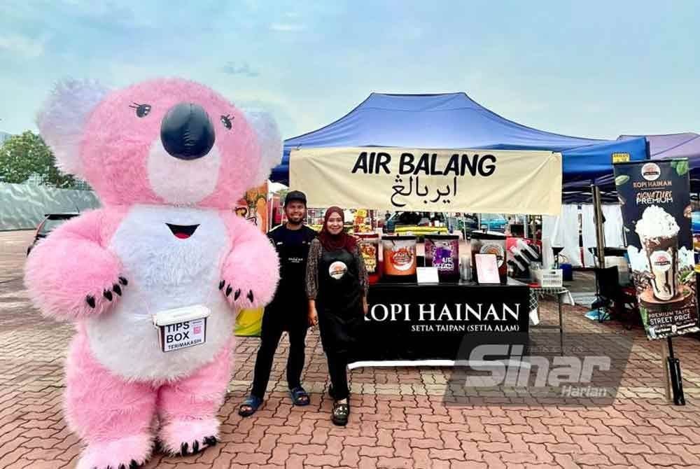 Muhammad Hafiz bersama isteri di hadapan tapak bazar Ramadan pada tahun lalu.
