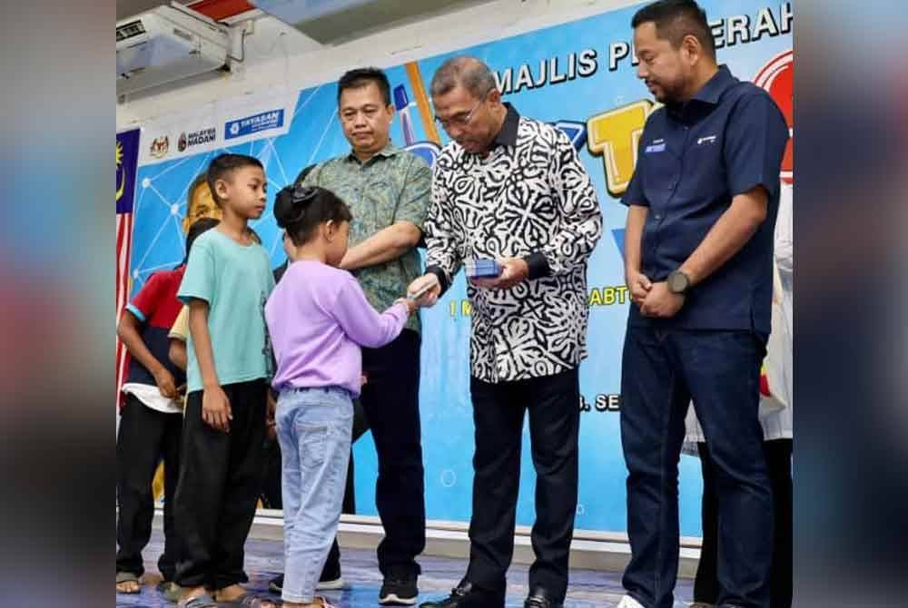 Azhar (dua dari kanan) menyampaikan sumbangan kepada penerima sempena Majlis Perasmian Bantuan Persekolahan YBR di Dewan Inderawati di sini pada Sabtu.