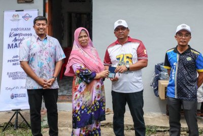 Badrul Hisham (dua, kanan) menyerahkan kad pengenalan gantian yang baharu kepada Ramlah Bidin (dua, kiri) menerusi Program Kampung Angkat Madani di Kampung Padang Tanjung pada Sabtu. Foto Bernama