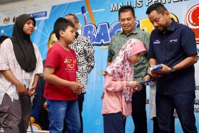 Syaiful Rizal (kanan) turut menyampaikan sumbangan kepada penerima sempena Majlis Perasmian Bantuan Persekolahan YBR di Dewan Inderawati di sini pada Sabtu.