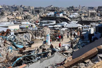 Penduduk Palestin berjalan di sebuah pasar bersebelahan runtuhan bangunan yang musnah di Jabalia, utara Semenanjung Gaza, ketika gencatan senjata antara Israel dan Hamas masih berlangsung. Foto AFP