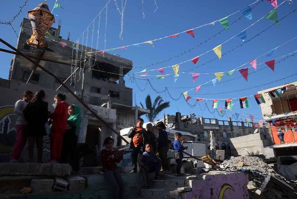 Kanak-kanak Palestin berkumpul di sebuah kawasan kejiranan yang dihiasi sederhana sempena kedatangan bulan suci Ramadan, di Khan Yunis, selatan Gaza.