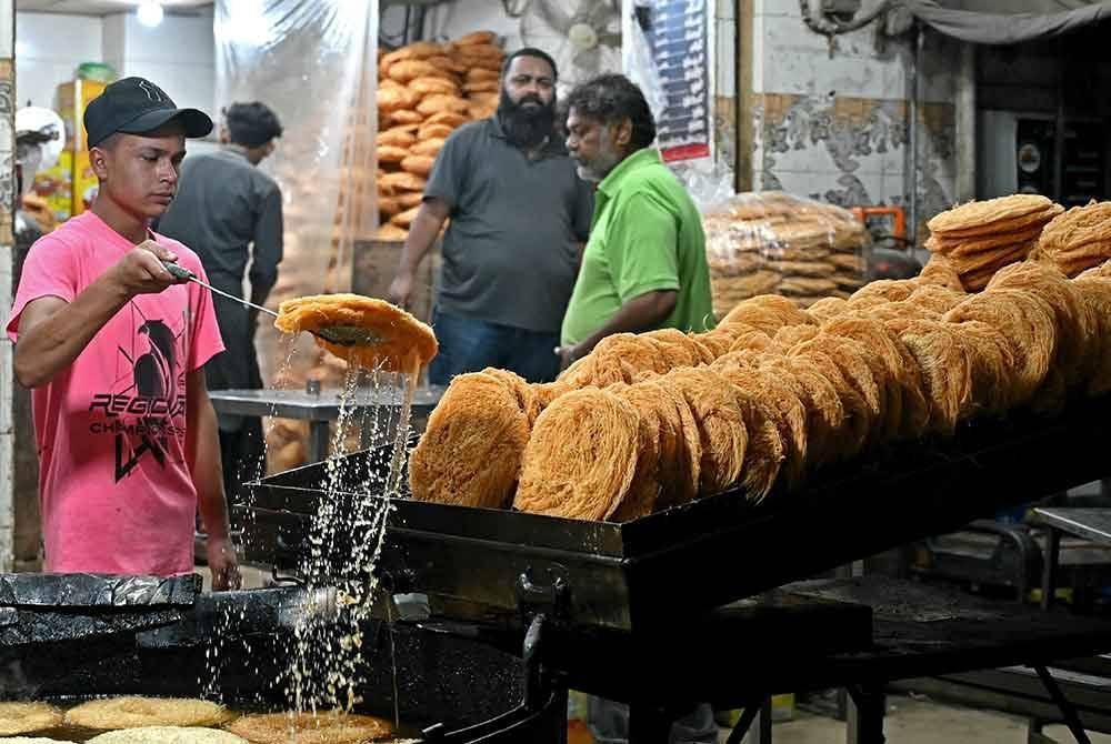 Seorang peniaga sedang menyediakan Khajla, pencuci mulut tradisional Pakistan sempena Ramadan, di Karachi.