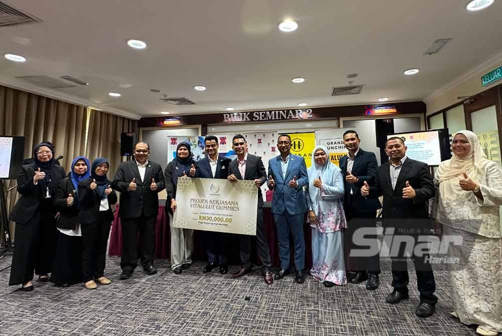 Dr Mohd Hannan (enam dari kiri) menyampaikan replika cek kepada Dr Arham (enam dari kiri) bagi projek kerjasama pembangunan produk makanan tambahan.