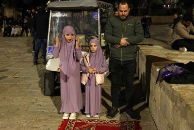 Seorang jemaah Palestin bersama kanak-kanak menunaikan solat sunat Tarawih di perkarangan Masjid Al-Aqsa, Baitulmaqdis. - AFP