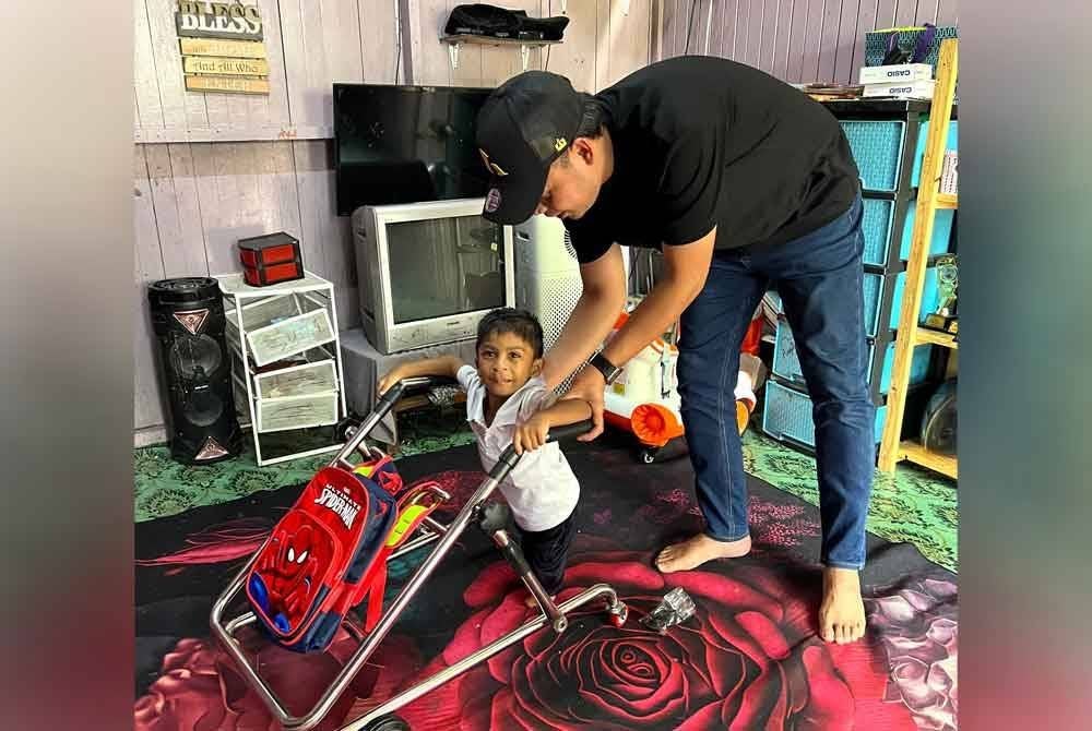 Amin membantu adik Shairid menggunakan tingkat beroda yang disumbangkan pihaknya.