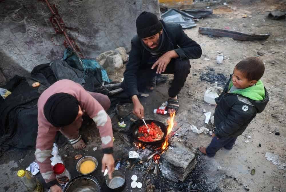 Sebuah keluarga menyediakan makanan untuk berbuka puasa di dapur sementara di luar khemah mereka.