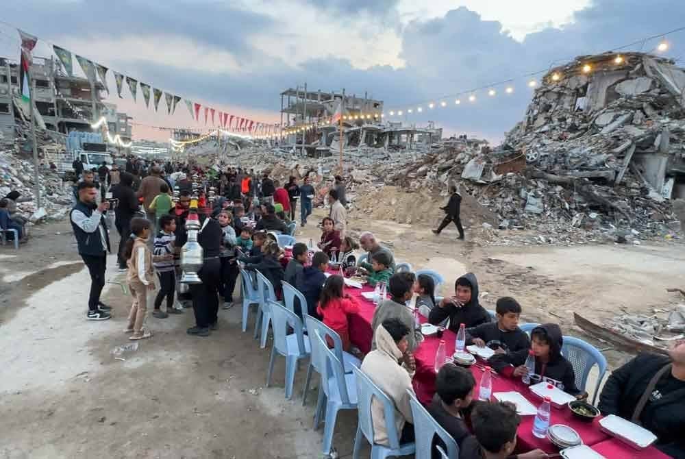 Penduduk Palestin berbuka puasa beramai-ramai di kawasan dikelilingi runtuhan struktur di Rafah, selatan Gaza.