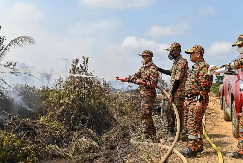 Anggota bomba melakukan kerja-kerja pemadaman di kawasan ladang kelapa yang masih terbakar.