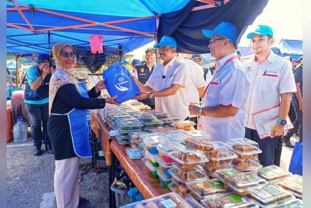 Razali mengedarkan kit pengendali makanan kepada pengusaha gerai sempena Majlis Pelancaran Walkabout Kempen Keselamatan Makanan di Bazar Ramadan di Tapak Bazar Ramadan.