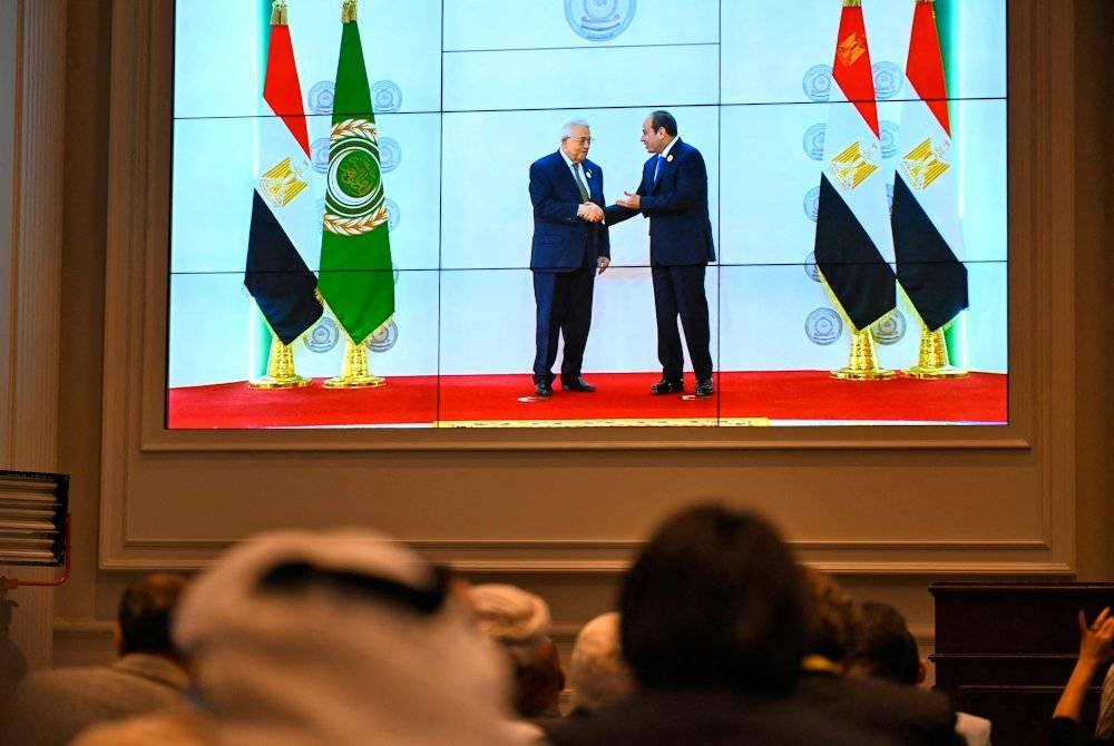 Skrin besar memaparkan Presiden Mesir Abdel Fattah al-Sisi (kanan) menyambut ketibaan Presiden Palestin Mahmud Abbas sidang kemuncak tergempar pemimpin Arab pada Selasa. Foto AFP