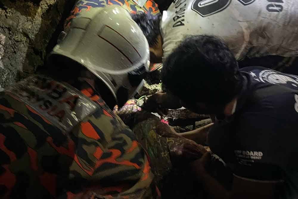 Pasukan bomba mengeluarkan mangsa yang tertimbus dalam kejadian tanah runtuh menimpa sebuah rumah di Kampung Lok Bunu, Sepanggar, Kota Kinabalu.