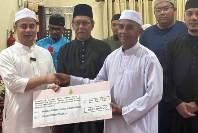 Mohamed Fahmi (kiri) menyerahkan replika cek bernilai RM5,000 bagi pembinaan laluan berbumbung di Dewan Serbaguna Masjid As-Siraj, Batu 23, Sungai Nibong, Sabak Bernam pada Rabu.