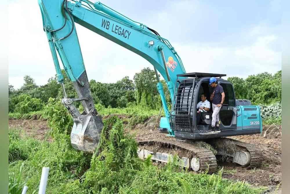 Zahari menyempurnakan gimik Perasmian pecah tanah di Kahang dengan menaiki jentera yang disediakan.