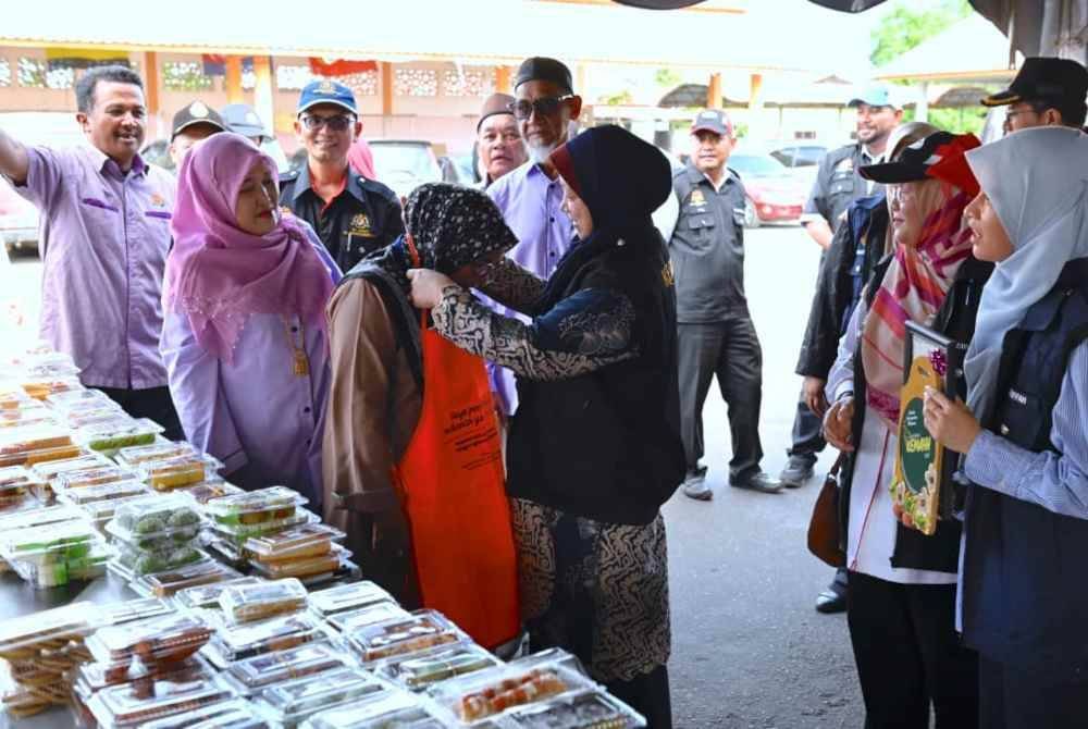 Dr Kasemani memakaikan apron kepada peniaga ketika kempen keselamatan makanan di bazar Ramadan Teluk Ketapang di Kuala Nerus, pada petang Rabu.
