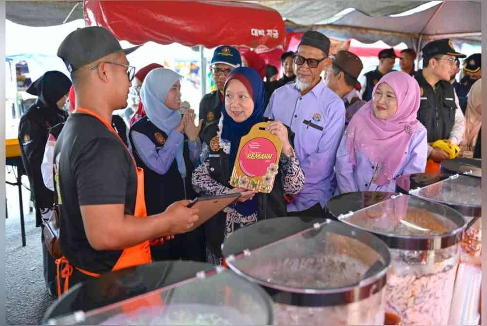 Dr Kasemani (tengah) menyampaikan plak penghargaan kepada peniaga ketika kempen keselamatan makanan di bazar Ramadan Teluk Ketapang di Kuala Nerus, pada petang Rabu.