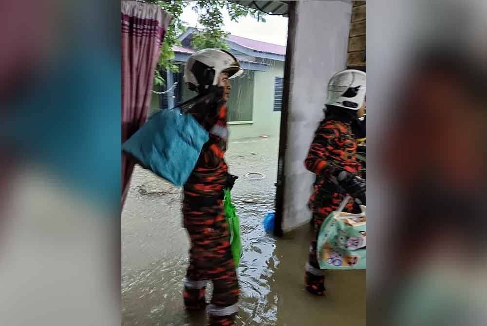 Anggota bomba ketika kerja-kerja menyelamatkan mangsa banjir di Lorong Pandan, Taman Kesidang di sini, pada pagi Khamis.