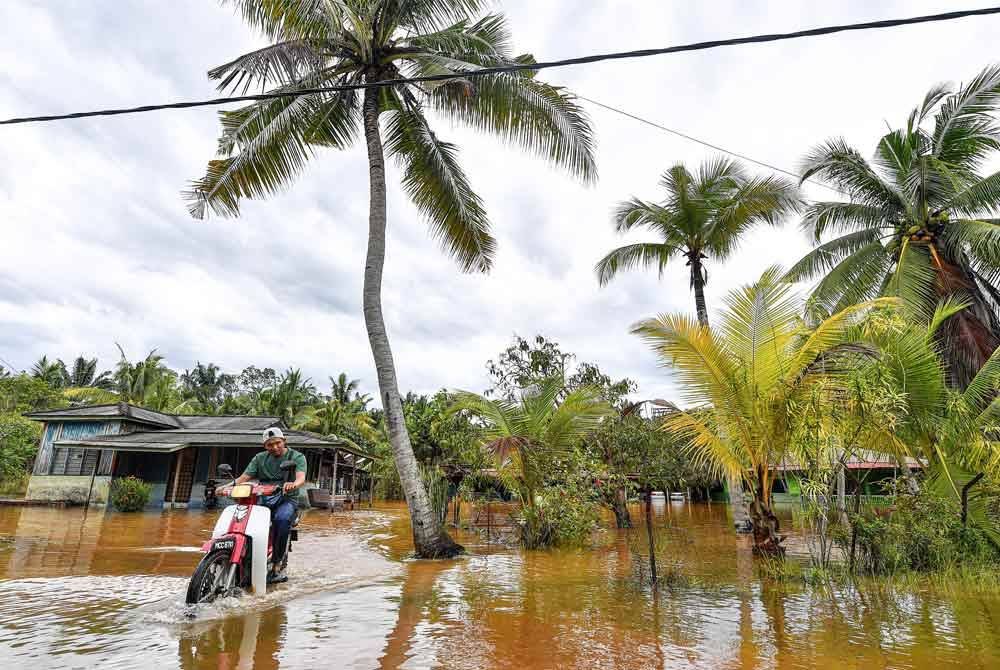 Penunggang motosikal meredah laluan di Kampung Segenting yang dinaiki air akibat limpahan air sungai berdekatan ekoran hujan lebat sejak Rabu. Foto Bernama