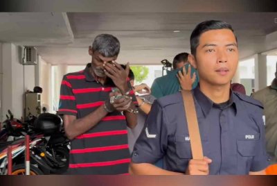 Tertuduh (kiri) diiringi anggota polis ketika dibawa ke mahkamah, pada Khamis.
