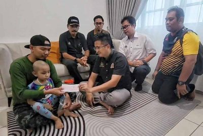 Seah Shoo Chin (duduk, tengah) menyampaikan cek sumbangan untuk Nur Sumayyah kepada Azroyhatta pada Khamis.