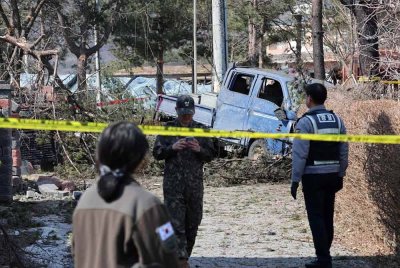 Tentera Korea Selatan dan seorang anggota polis berdiri di sebelah kenderaan yang rosak selepas insiden bom di sebuah kampung di Pocheon. Foto AFP