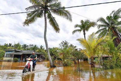 Penunggang motosikal meredah laluan di Kampung Segenting yang dinaiki air akibat limpahan air sungai berdekatan ekoran hujan lebat sejak Rabu. Foto Bernama