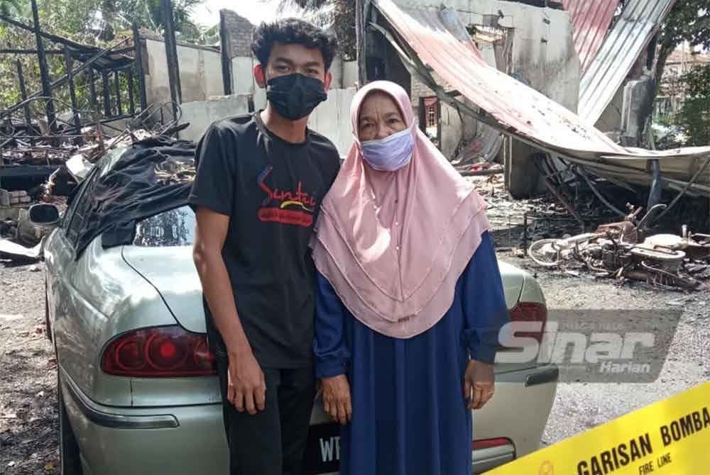 Adam bersama ibunya, Anisah Arifin, 62, di hadapan rumah mereka yang musnah dalam kebakaran di Jalan Taman Sri Tanjung, Wakaf Bharu, Tumpat pada Jumaat.