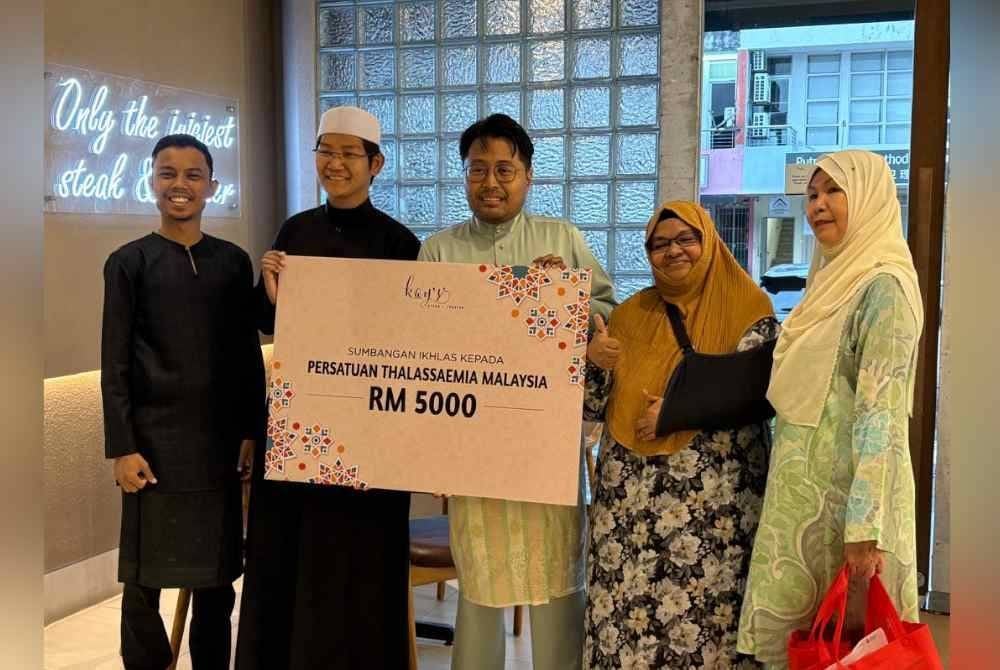 Aizuddin (tengah) menyerahkan sumbangan berjumlah RM5,000 kepada Irham (dua dari kiri) dalam Majlis CSR Ramadan Kay's Steak & Lobster, di Subang Jaya, Selangor pada Khamis.