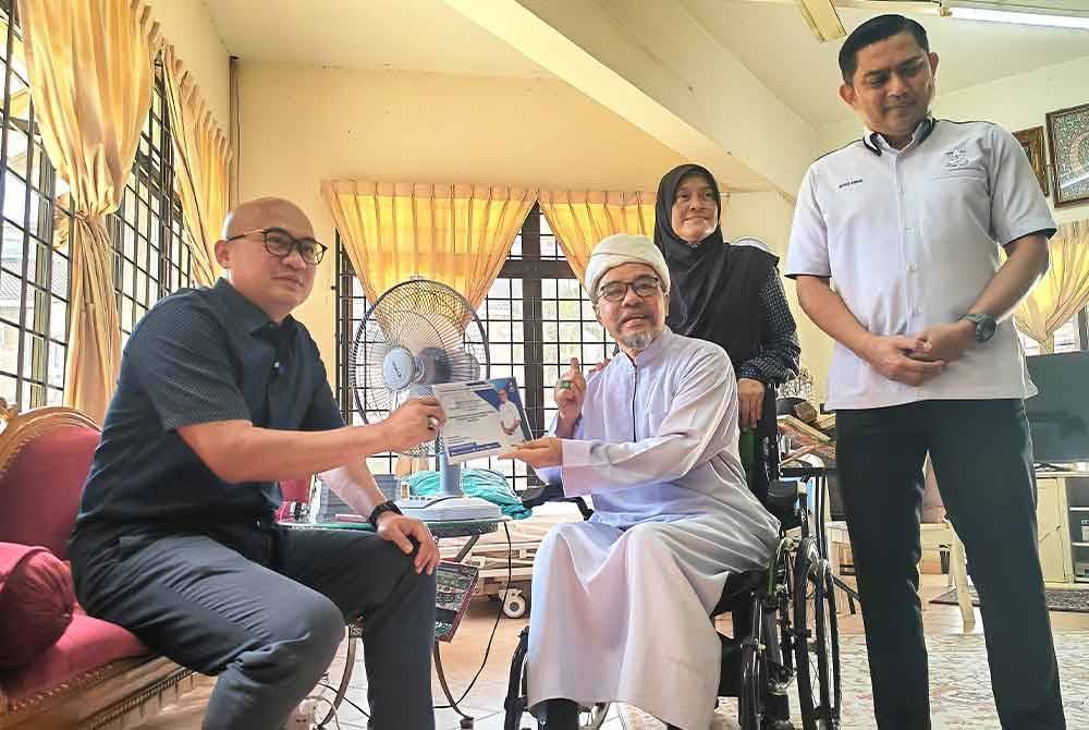 Syeqal menerima sumbangan daripada kerajaan negeri yang disampaikan Fadzli (kiri).