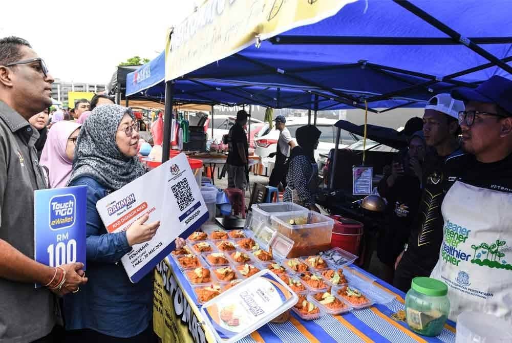 Timbalan Menteri Perdagangan Dalam Negeri dan Kos Sara Hidup, Dr Fuziah Salleh (dua dari kiri) menyampaikan replika kad diskaun khas Rahmah Madani kepada pengusaha Bazar Ramadan semasa melawat Bazar Ramadan di Jalan Mahkamah, Bayan Lepas pada Jumaat. Foto Bernama