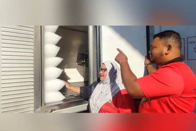 Ahmad Yusop (kanan) dan Suzana (kiri) melihat pekerja menyusun ais kuib dalam lori.