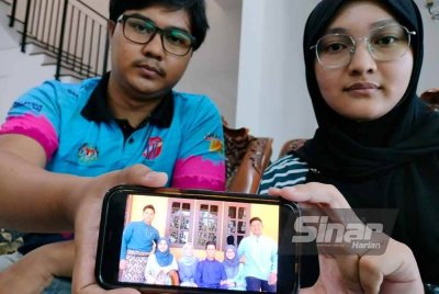 Suraiya dan Muhammad Amir menunjukkan gambar kenangan beraya bersama bapa mereka tahun lalu.