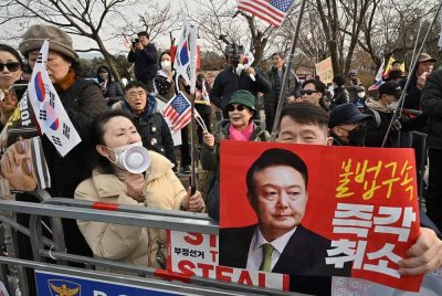 Penyokong bekas Presiden Korea Selatan yang ditahan dan dipecat, Yoon Suk Yeol, memegang plakad merah dengan gambar Yoon serta tulisan 'Batalkan penahanan tidak sah segera!' ketika berhimpun di luar Pusat Tahanan Seoul di Uiwang. - AFP