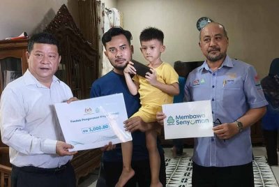 Mohammad Afiq Akhmal menerima faedah PERKESO arwah isterinya yang diserahkan Chon Siang bersama Hisham sempena program ziarah prihatin dan penyerahan faedah PERKESO di rumah keluarganya di Taman PSJ di Kuantan pada Khamis.