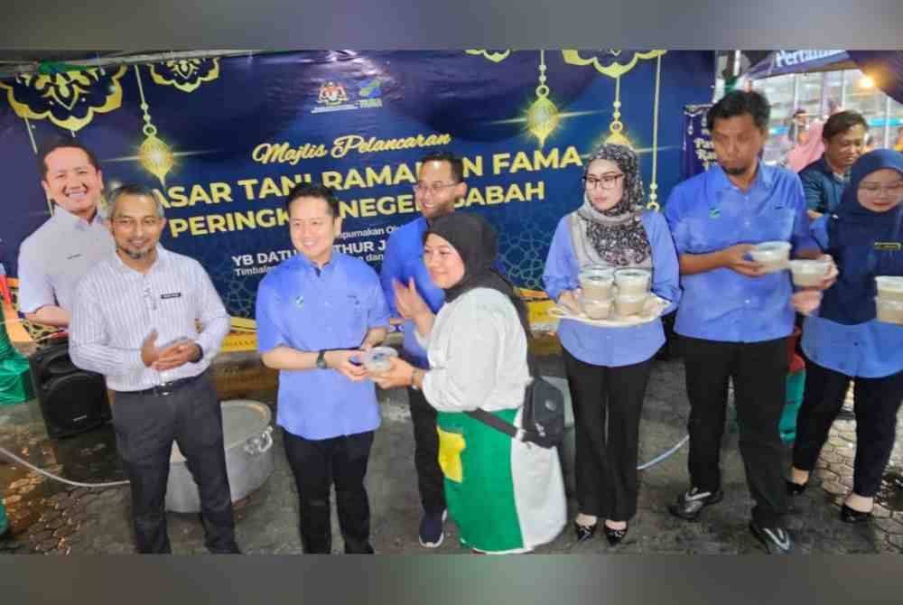 Arthur menyampaikan bubur kepada orang ramai yang hadir pada Majlis Pelancaran Bazar Ramadan Peringkat Sabah di Pasar Tani Asia City, Kota Kinabalu.