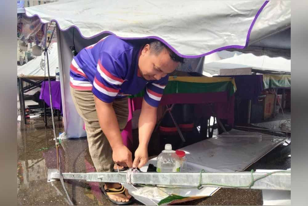 Azwan membuka ikatan khemah yang terbalik selepas ribut kuat awal pagi Sabtu