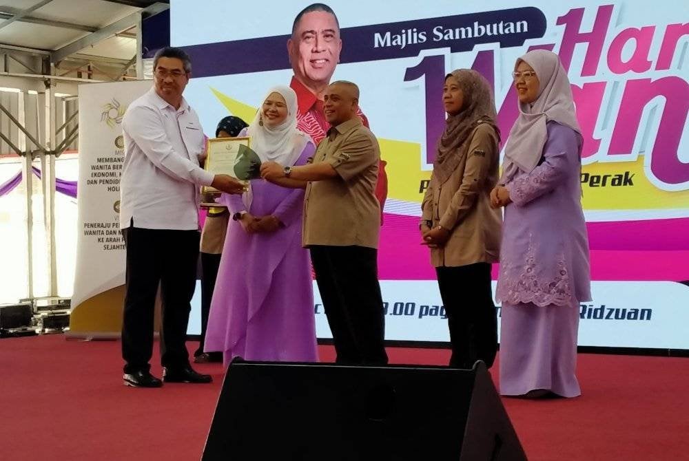 Saarani (tengah) menyampaikan cenderahati kepada wakil agensi terlibat sempena Sambutan Hari Wanita Peringkat Negeri Perak di Laman Seri Ridzuan pada Sabtu.