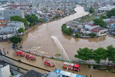 Anggota bomba menggunakan pam berkuasa tinggi untuk mengalihkan air banjir dari Jalan Jatinegara Barat di Jakarta Timur ke Sungai Ciliwung.