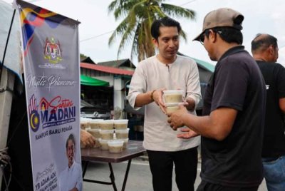 Adam Adli mengagihkan bubur lambuk kepada penduduk setempat sempena Majlis Peluncuran Santuni MADANI di Kampung Baru Penaga hari ini. Foto Bernama