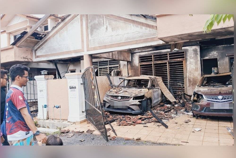 Ahmad Zul Wafi (kiri) melihat keadaan rumah dan keretanya yang musnah dalam kebakaran melibatkan tujuh unit rumah teres dua tingkat pada awal pagi Sabtu.