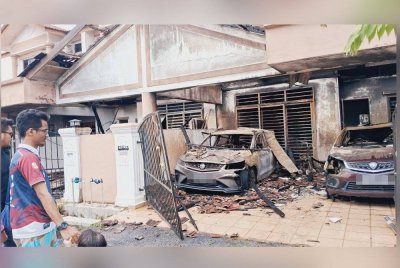 Ahmad Zul Wafi (kiri) melihat keadaan rumah dan keretanya yang musnah dalam kebakaran melibatkan tujuh unit rumah teres dua tingkat pada awal pagi Sabtu.