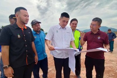 Baderul Amin (kanan) memberi penerangan kepada Moii Lye mengenai aktiviti tanah secara haram yang dilakukan di dua lot tanah di Permatang Ara, pada Ahad.