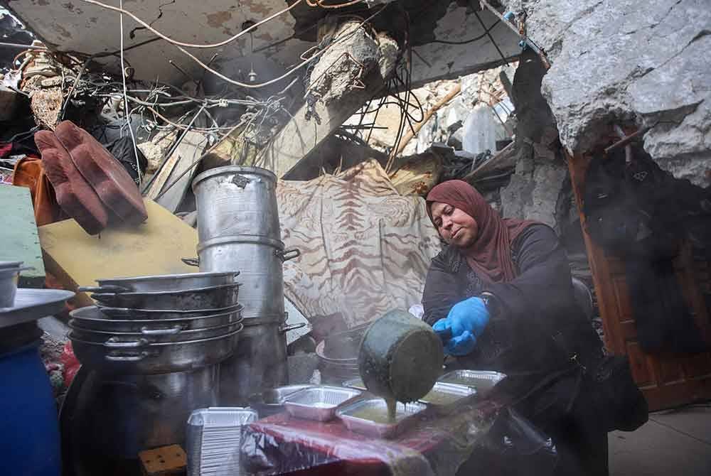 Seorang wanita Palestin menyediakan makanan bagi pihak dapur amal, untuk diagihkan kepada keluarga yang kehilangan tempat tinggal di Beit Lahia di utara Semenanjung Gaza, sebelum jamuan buka puasa. - Foto AFP
