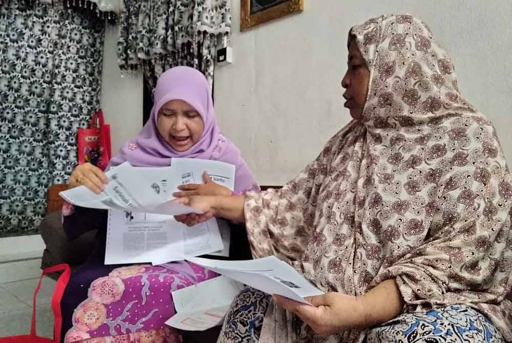 Sarimah (kanan) menunjukkan keratan akhbar kepada Dr Hafidzah yang mewakili Mohd Na'im ketika kunjungan di kediaman warga emas itu.