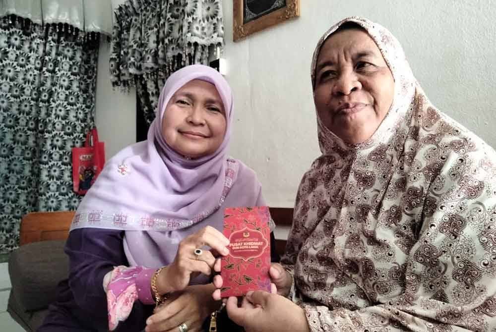 Dr Hafidzah (kiri) menyampaikan sumbangan daripada Mohd Na'im kepada Sarimah.